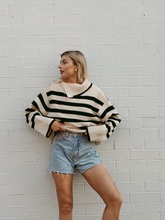 a lady wears a loose fit striped sweater with a denim shorts